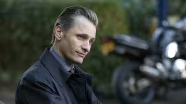 Nikolai Luzhin (Viggo Mortensen) looks aside with a motorcycle behind him
