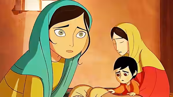 Parvana (Saara Chaudry) sits with a concerned expression beside a young boy and another woman
