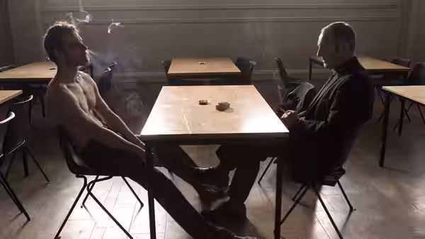 Bobby Sands (Michael Fassbender) and Priest (Liam Cunningham) sit at a table amid cigarette smoke