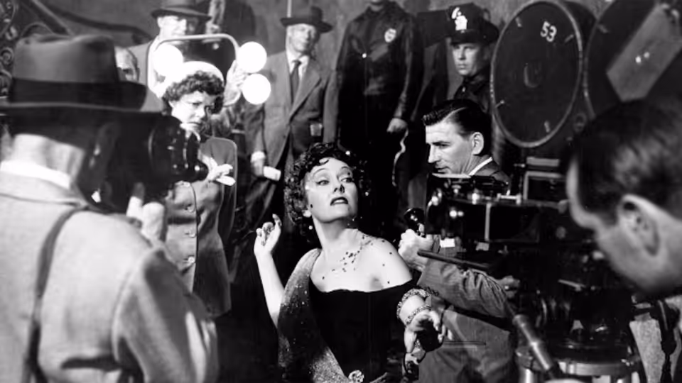 Norma Desmond (Gloria Swanson) gestures among cameras and crew on a film set