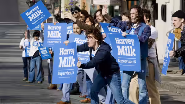 Protesters marching outdoors carrying blue Harvey Milk campaign signs