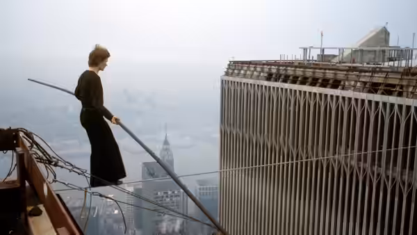Philippe Petit stands on a skyscraper ledge holding a long balancing pole
