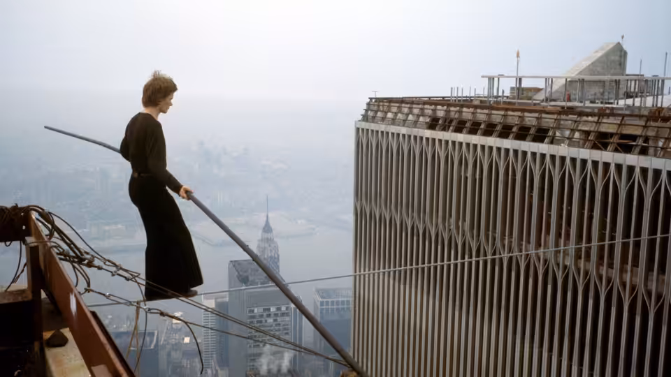 Philippe Petit stands on a skyscraper ledge holding a long balancing pole