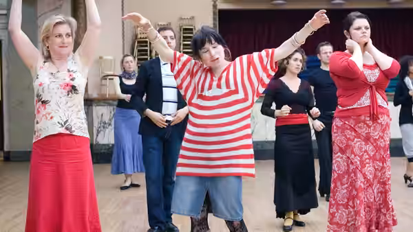 a group of women dancing together in a studio with mirrors and a piano