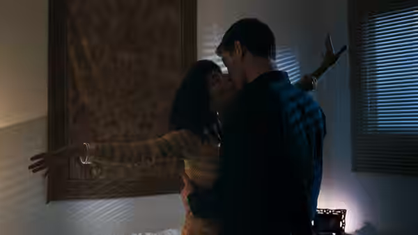 a couple kissing passionately in a bedroom with one arm extended