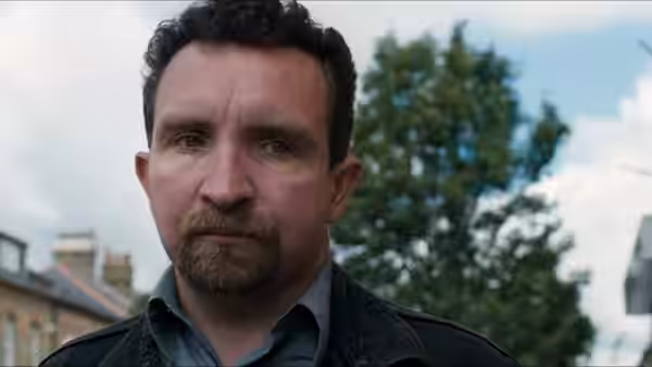 a man with a beard and curly hair staring intently outdoors