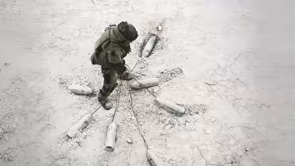 A bomb disposal expert examines improvised explosive devices on cracked ground