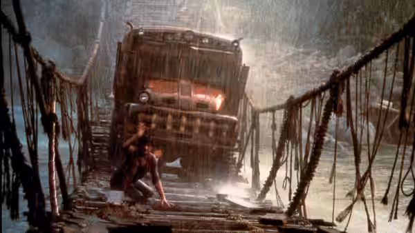 A man braces against a rope bridge as a loaded truck lurches through spray