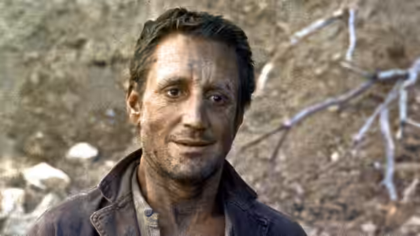 Scanlon (Roy Scheider) stands outdoors against a rocky hillside
