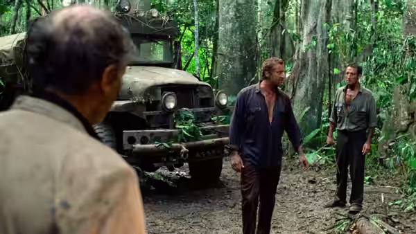 Men stand beside a parked truck in a dense jungle clearing