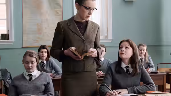 Headmistress (Emma Thompson) stands in a classroom holding an open book