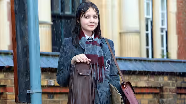 Jenny (Carey Mulligan) stands in falling rain wearing school uniform