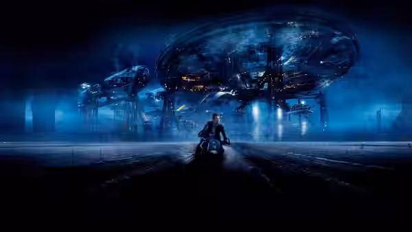 a rider on a motorcycle approaching a massive illuminated structure at night