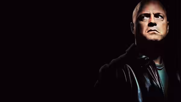 Vic Mackey (Michael Chiklis) gazing sideways against a black background