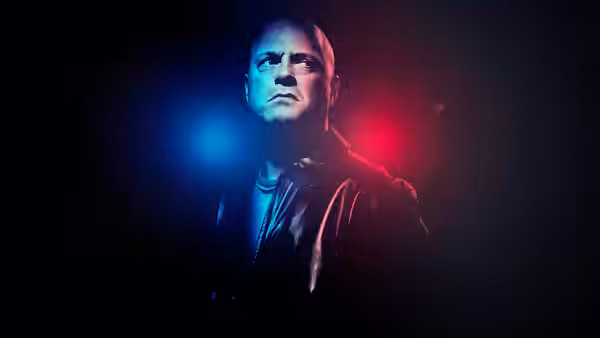 Vic Mackey (Michael Chiklis) standing in darkness under blue and red lights