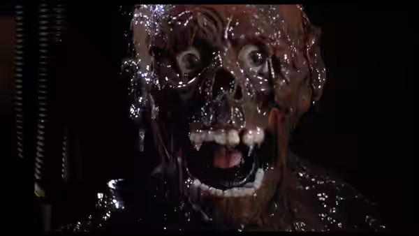 A glistening, decomposing zombie gapes toward the camera in darkness
