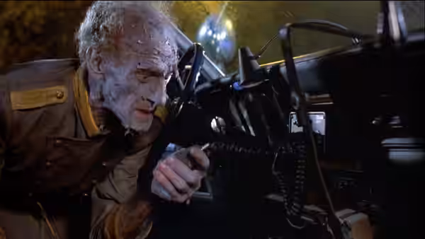 An elderly zombie reaches through a vehicle window toward the interior