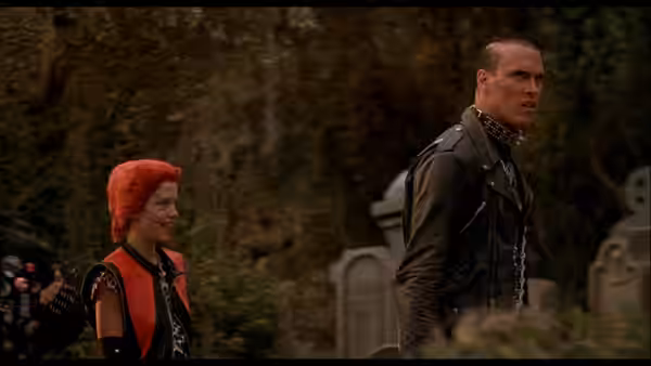 Trash and a leather-clad punk walk among gravestones in a cemetery