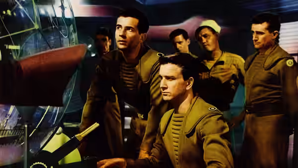 Commander Adams and uniformed crewmen gather around a control station