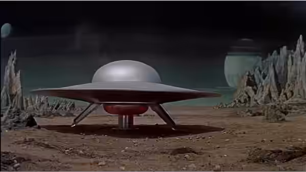 A disc-shaped spacecraft rests on a barren alien landscape between towering rock formations
