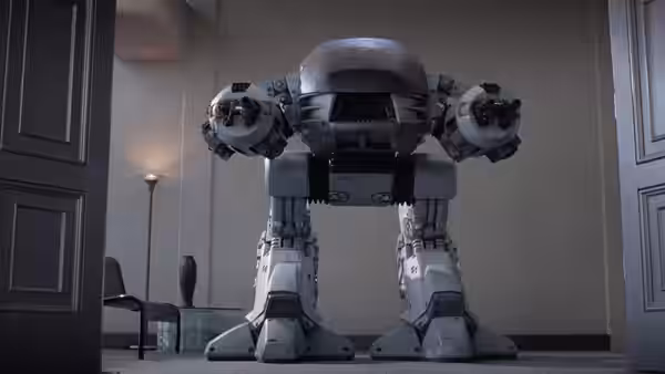 A large white robotic enforcement droid standing in an office doorway