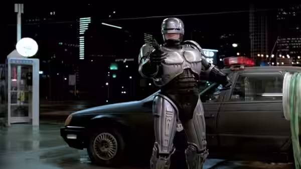 RoboCop (Peter Weller) aiming his gun beside a police car at night