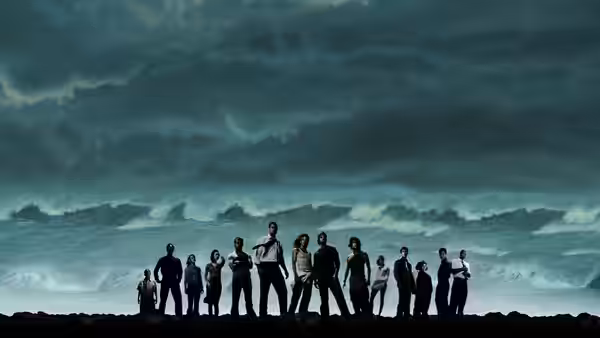 Group lined up on a rocky shore facing a stormy sea under dark clouds