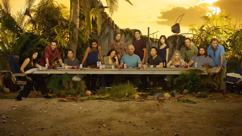 Group seated at a long table outdoors in a tropical clearing at sunset