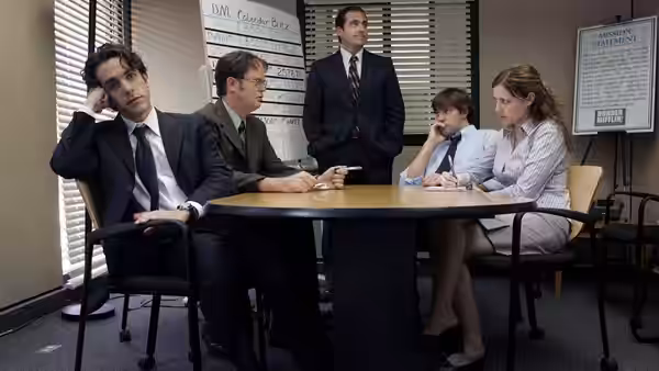 Jim Halpert (John Krasinski) sits at a conference table with colleagues