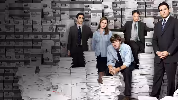 Five colleagues pose among stacks of white boxes in an office