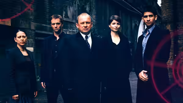 Harry Pearce (Peter Firth) and team pose in a dark brick alley with red graphics