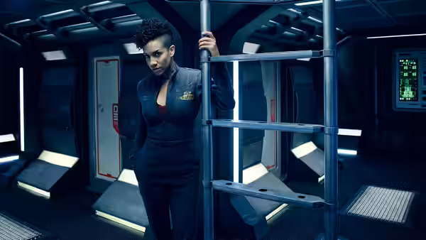 Bobbie Draper grips a ladder in a spacecraft corridor