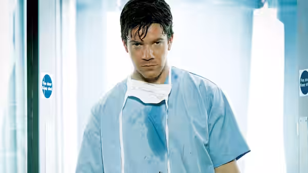 Rob Lake (Max Beesley) in stained scrubs stands in hospital corridor