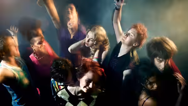 Young people dancing together in a dark smoky club with raised arms
