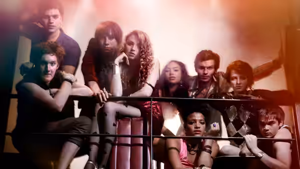 Group of young adults leaning on a metal railing in a hazy red-lit room