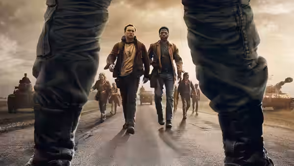 Two young men walking on a road towards the camera with vehicles behind