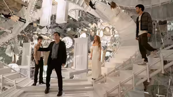 Four people stand amid floating debris inside a room of shattered mirrors