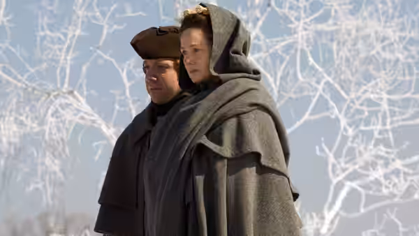 John Adams (Paul Giamatti) and Abigail Adams (Laura Linney) standing in snowy woods