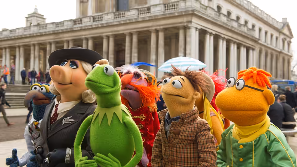 Kermit and the Muppets gather outside a grand columned building in London