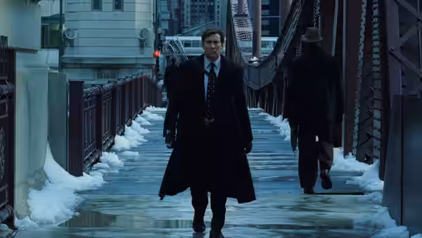 David Spritz (Nicolas Cage) walks across a snow-covered pedestrian bridge in a long coat