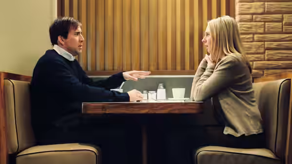 David Spritz (Nicolas Cage) gestures across a restaurant table to a woman