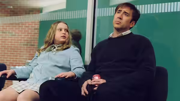 David Spritz (Nicolas Cage) sits beside his daughter in a waiting room, holding a soda