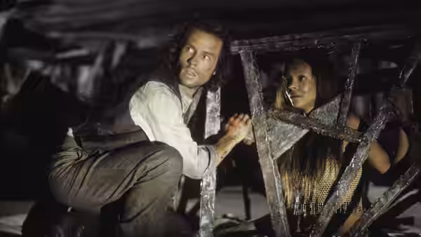 Alexander Hartdegen (Guy Pearce) and Mara (Samantha Mumba) hide beneath a wooden structure