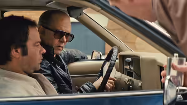 Whitey Bulger (Johnny Depp) sits behind the wheel as a passenger looks on