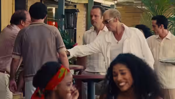 Whitey Bulger (Johnny Depp) reaches across a table at an outdoor gathering
