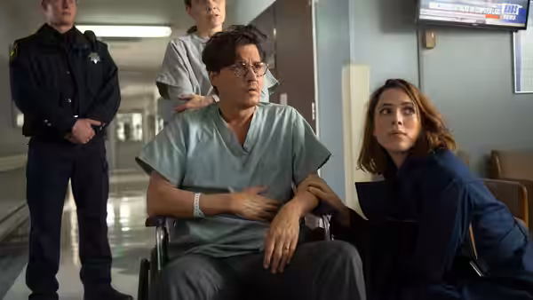 Will Caster (Johnny Depp) sits in a hospital wheelchair beside Evelyn Caster (Rebecca Hall)