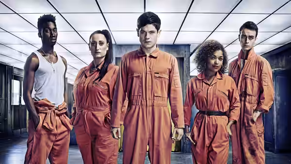 five people in orange jumpsuits standing in a lit corridor