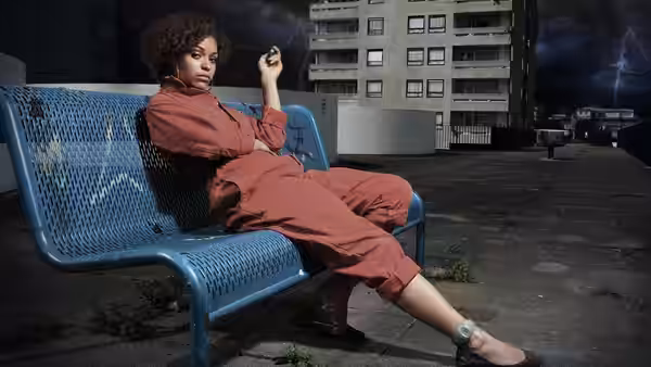 woman in red jumpsuit reclining on a blue bench with phone