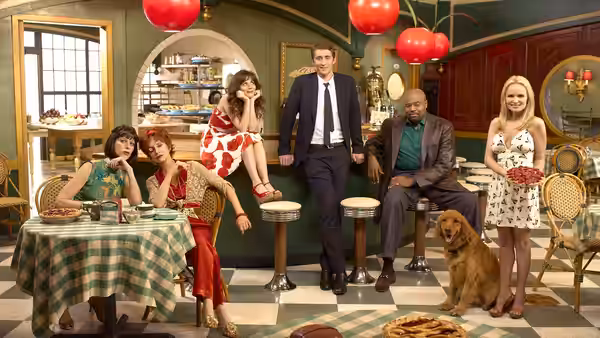 Ned (Lee Pace) stands with cast members in a vibrant diner