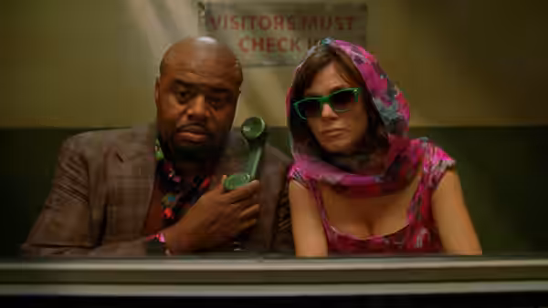 Emerson Cod (Chi McBride) holds a green phone beside a woman